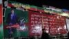 পাকিস্তানের ওয়াজিরাবাদে বন্দুক হামলার কয়েক ঘণ্টা পর পাকিস্তানের সাবেক প্রধানমন্ত্রী ইমরান খানের রাজনৈতিক সমাবেশে ব্যবহৃত কনটেইনার ট্রাকের সামনে একজন পুলিশ কর্মকর্তা পাহারা দিচ্ছেন। ৩ নভেম্বর, ২০২২।