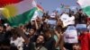 People wave the regional flag and hold placards during a rally in Dohuk in the autonomous Kurdish region of northern Iraq, Sept. 5, 2023, to protest unpaid salaries for civil servants.