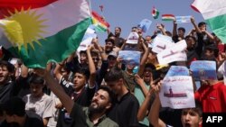 People wave the regional flag and hold placards during a rally in Dohuk in the autonomous Kurdish region of northern Iraq, Sept. 5, 2023, to protest unpaid salaries for civil servants.