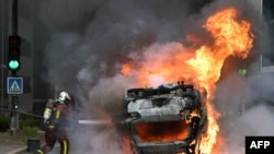 A firefighter extinguishes a burning car at the end of a commemoration march for a teenage driver shot dead by a policeman, in the Parisian suburb of Nanterre, France, June 29, 2023.
