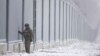 FILE - A Polish border guard stands next to the border wall in Nomiki in November 2022. Poland’s governing party is being rocked by reports that Polish consulates issued visas in Africa and Asia in exchange for bribes, opening the door for migrants to enter the EU.