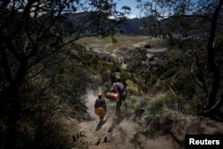 Pria Hindu Tengger membawa alat musik tradisional saat berjalan menuruni gunung usai melakukan "Mendhak Tirta", menjelang festival Yadnya Kasada di Taman Nasional Bromo Tengger Semeru, Pasuruan, Jawa Timur, 19 Juni 2024. (REUTERS/Willy Kurniawan)
