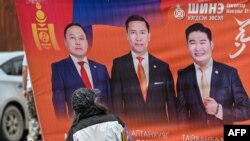 Seorang perempuan melihat poster calon peserta pemilu parlemen di jalan Ulaanbaatar, 25 Juni 2024, menjelang pemilu 28 Juni. (Hector RETAMAL / AFP)