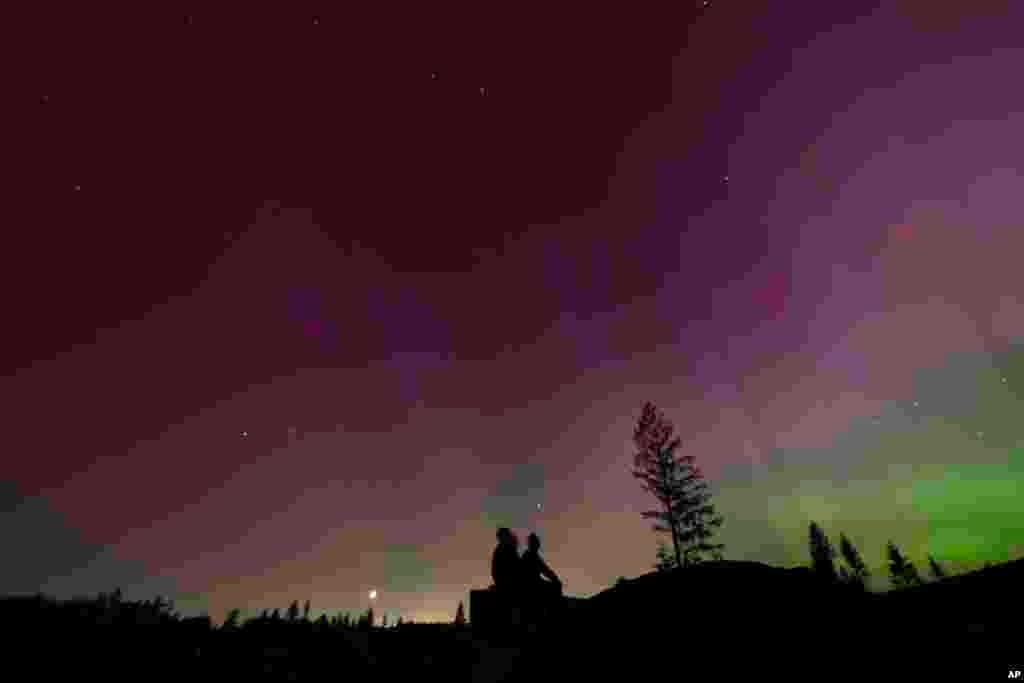 In this image taken with a long exposure, people look at the night sky towards the northern lights, in Estacada, Oregon, May 10, 2024.