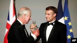 French President Emmanuel Macron, right, and Britain's King Charles III toast during a state dinner in the Hall of Mirrors at the Chateau de Versailles in Versailles, west of Paris, Sept. 20, 2023.