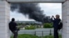 Foreign journalists report from an observation point while smoke rises after a Russian attack in Kharkiv, Ukraine, May 17, 2024.