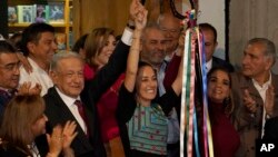 Mexican President Andres Manuel Lopez Obrador raises the hand of Claudia Sheinbaum, the ruling party's candidate for the upcoming presidential elections, during a ceremony to giver her the party's command staff, in Mexico City, Sept. 7, 2023.