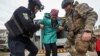 A police officer and a volunteer help a Vovchansk resident evacuate to Kharkiv due to Russian military strikes near the town of Vovchansk in the Kharkiv region, Ukraine, May 17 , 2024.