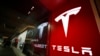 FILE - A sign bearing the Tesla company logo is displayed outside a Tesla store in Cherry Creek Mall in Denver, Colorado, Feb. 9, 2019.