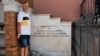 Mauro Petrarca poses for a photo next to a memorial in honor of six men, including his great grandfather, who were hanged by the German army in 1943, in Fornelli, Italy, Aug. 2, 2023. 