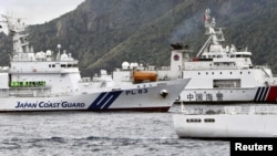 Sebuah kapal Garda Pantai China berlayar di dekat kapal Garda Pantai Jepang Kabira di lepas pantai Pulau Uotsuri, salah satu dari sekelompok pulau yang disengketakan yang disebut Kepulauan Senkaku, di Laut China Timur, 27 April 2024. (Kyodo via Reuters)