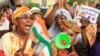 FILE - A person holds a paper that reads 'We no longer want France' as Nigerien women demonstrate in support of the putschists in front of French Army headquarters, in Niamey, Niger, Aug. 30, 2023.