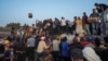 Palestinians storm trucks loaded with humanitarian aid brought in through a new U.S.-built pier in the central Gaza Strip, May 18, 2024.