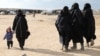 FILE - A woman holds a child's hand in the al-Hol camp, Syria, Jan. 8, 2020. After U.S.-backed and Kurdish-led fighters defeated the Islamic State group in Syria in March 2019, thousands of IS fighters and their families were taken to al-Hol.