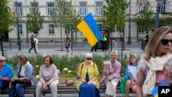 Люди з українськими прапорами у Вільнюсі в Литві, де станом на серпень 2023 р. зареєстровані понад 72 000 біженців від російської війни в Україні. Фото 11 липня 2023 р.