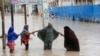FILE - Women walk through floodwaters after heavy rainfall in Mogadishu, Somalia, Nov. 20, 2023. 