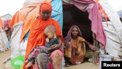 সোমালিয়ার রাজধানী মোগাদিশুর উপকণ্ঠে, অভ্যন্তরীণভাবে বাস্তুচ্যুত লোকেদের জন্য একটি অস্থায়ী আশ্রয় কেন্দ্রের বাইরে, ভরা বর্ষা মৌসুমেও ক্রমবর্ধমান খরায় আক্রান্ত একজন সোমালি মহিলা তার ৩ বছরের মেয়েকে আগলে রেখেছেন। ২৩ সেপ্টেম্বর, ২০২২।