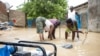 Des habitants du quartier d'Amtoukiou creusent un trou pour pomper l'eau de la cour de la maison de NDjamena, le 5 août 2022.