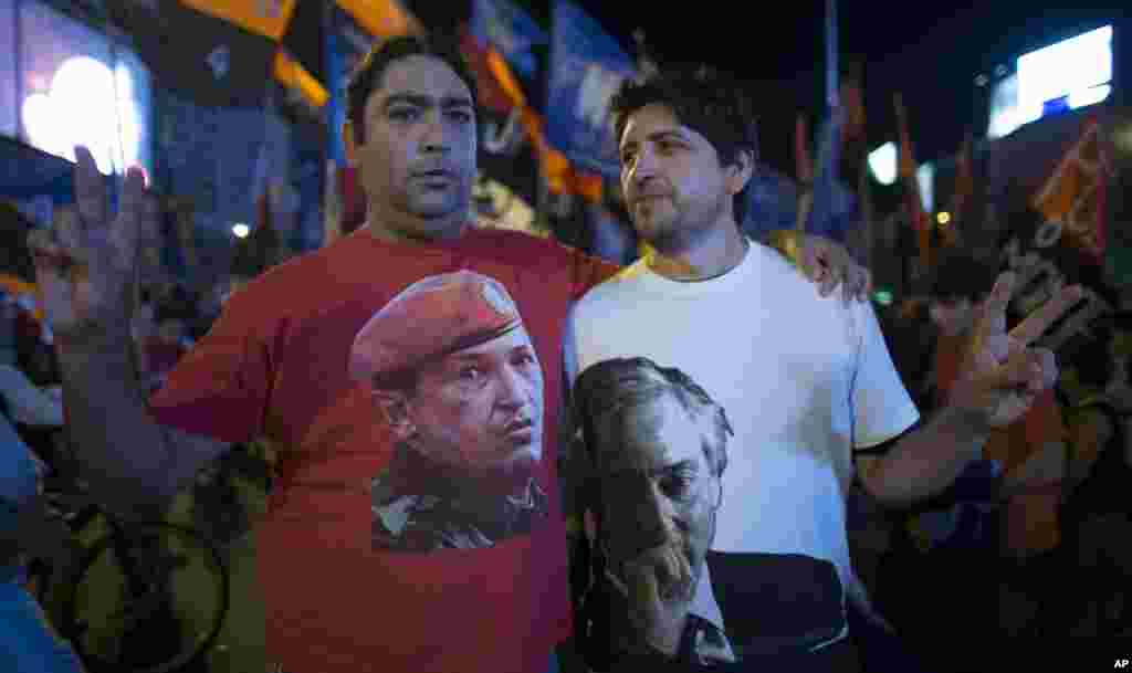 Argentine supporters of Venezuelan President Hugo Chavez pose for pictures wearing T-shirts with images of Chavez, left, and Argentina's late President Nestor Kirchner, right, in Buenos Aires, Argentina, March 5, 2013.