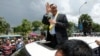 FILE - In this Aug. 16, 2015 file photo, Sam Rainsy, leader of the opposition Cambodia National Rescue Party (CNRP), waves from a car upon his arrival at Phnom Penh International Airport in Phnom Penh, Cambodia as hundreds of cheering supporters greeted him on his return from a trip abroad. The head of Cambodia's opposition party has announced his resignation from the group after the country's long-serving prime minister announced plans for a law that could lead to the party's dissolution. Rainsy announced his resignation Saturday, Feb. 11, 2017 in a letter to his Cambodia National Rescue Party.(AP Photo/Heng Sinith, File)