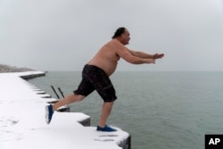 FILE - "The Great Lake Jumper" Dan O'Conor takes a plunge into the frigid waters of Lake Michigan, Jan. 26, 2023, in Chicago.