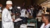 Le principal candidat de l'opposition Cellou Dalein Diallo reçoit son bulletin de vote d'un responsable de la commission électorale dans un bureau de vote à Conakry le 18 octobre 2020, lors des élections présidentielles en Guinée. (Photo par CELLOU BINANI / AFP)