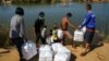 Pengungsi, yang melarikan diri dari gejolak pertempuran antara tentara Myanmar dan kelompok pemberontak dan menetap sementara di Tepi Sungai Moei, menerima bantuan dari Thailand di Mae Sot, Thailand, 7 Januari 2022. ( Foto: REUTERS/Athit Perawongmetha)