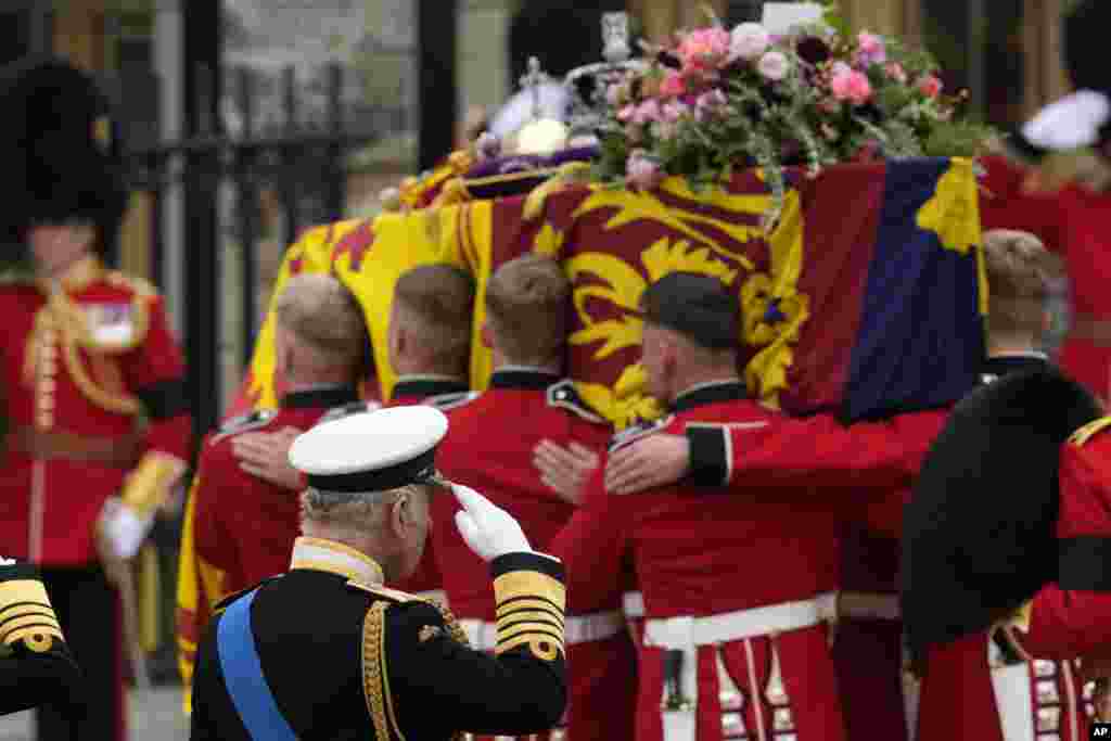 King Charles III salutes as the coffin of his mother Queen Elizabeth is carried into Westminster Abbey for her funeral in central London, Sept. 19, 2022.