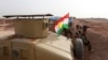 A Kurdish flag is seen next to Peshmerga fighters taking position with their weapons on the frontline against the Islamic State, on the outskirts of Mosul, Iraq, Jan. 26, 2015.