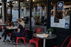 Customers eat at restaurant next to signs indicating discounts off food, in central London, Aug. 3, 2020.