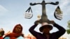 A protester from Boeung Kak lake holds a cutout of a scale symbolizing justice as she joins other villagers, who were allegedly evicted from their homes without adequate compensation, during a rally in front of the Justice Ministry in Phnom Penh, Cambodia, file photo. 