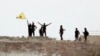 Fighters with the Kurdish People's Protection Units, or YPG, wave their yellow triangular flag on the outskirts of Tal Abyad, Syria, June 15, 2015.