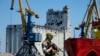 FILE - A Russian soldier guards a pier with the grain storage in the background at an area of the Mariupol Sea Port which has recently started its work after heavy fighting in Mariupol, on the territory which is under the Government of the Donetsk People'