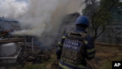 Un bombero trata de apagar el fuego de una casa luego que proyectiles rusos atacaran un área residencial, el sábado 9 de julio.