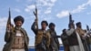 FILE - Afghan militiamen raise their weapons as they stand guard in the Achin district of Nangarhar province, Afghanistan, Dec. 27, 2015.