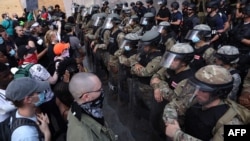 FILE - Demonstrators stand in front of the D.C. National Guard and other law enforcement officers during a peaceful protest against police brutality and the death of George Floyd, in Washington, June 3, 2020.