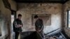 Kashmiri Muslim student Hilal Ahmed Hajam, left, and Nasir Ahmed Mir inspects the damage of a partially burned government high school in Goripora, outskirts of Srinagar, India controlled Kashmir, Nov. 1, 2016. At least 25 schools have been torched in the past three months, amid widespread unrest. 