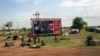 Civilians preparing to flee from renewed attacks gather in front of a sign celebrating the second anniversary of South Sudan's independence in Bentiu, Unity state of South Sudan, April 20, 2014.
