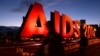 People walk past an "AIDS 2014" sign promoting the 20th International AIDS Conference in Melbourne on the eve of the concluding session of the conference, July 24, 2014. 