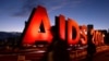 People walk past an "AIDS 2014" sign promoting the 20th International AIDS Conference in Melbourne on the eve of the concluding session of the conference, July 24, 2014. 