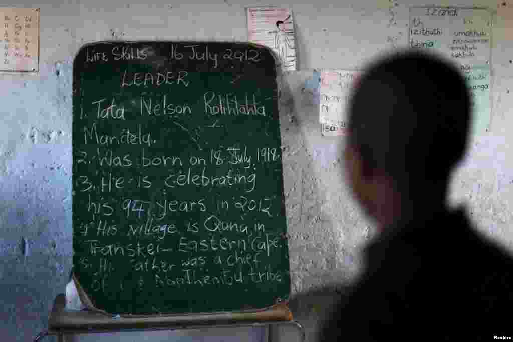 Crianças de uma escola lêem a história que o ex-Presidente sul-africana Nelson Mandela escreveu num quadro negro, na entrada da biblioteca da Fundação Bill Clinton na celebração do Dia de Mandela, numa escola de in Qunu, Jul. 17, 2012.