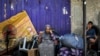 A woman and child wait with belongings before evacuating from Rafah in the southern Gaza Strip on May 11, 2024, amid the ongoing conflict in the Palestinian territory between Israel and Hamas.
