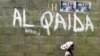 FILE - A girl walks past a wall with graffiti about the al-Qaida network in Kano, Nigeria, April 18, 2003. An airstrike this week by U.S. Africa Command targeted Al-Qaida in the Islamic Maghreb, near al-Uwaynat, Libya.