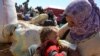 FILE - A Syrian refugee feeds her baby at a border crossing near Suruc, Turkey, Oct. 1, 2014.