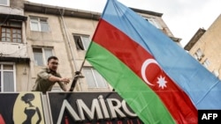 Seorang penduduk ibu kota Azerbaijan mengibarkan bendera nasional di Baku pada 20 September 2023, untuk mendukung serangan negara di wilayah Nagorno-Karabakh. (Foto: AFP)