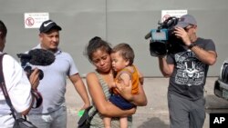 Adalicia Montecino and her husband Rolando Bueso Castillo are surrounded by the media as they walk with their year-old son Johan Bueso Montecinos, who became a poster child for the U.S. policy of separating immigrants and their children, in San Pedro.