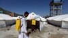 Afghan health workers in protective suits spray disinfectant on tents to help curb the spread of the coronavirus in the first quarantine camp for Afghan refugees crossing Torkham border from Pakistan to Afghanistan, April 4, 2020.
