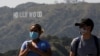 People wearing face masks walk past the Hollywood sign in the distance, after a partial reopening of Los Angeles hiking trails during the outbreak of the coronavirus disease (COVID-19) at Griffith Park in Los Angeles, California, U.S., May 9, 2020. REUTER