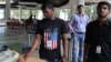 FILE - An Infosys employee sports a t-shirt featuring a U.S. flag as he buys coupons for lunch while others wait for their turn at company headquarters in Bangalore, India, April 15, 2016. 