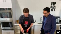 Memphis Meats CEO Uma Valeti, right, watches chicken produced in a laboratory from chicken cells being cooked in Emeryville, California, April 11, 2019. 